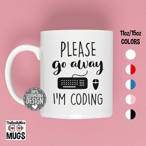 Puede incluir: Taza de cerámica blanca con texto negro que dice "PLEASE go away I'M CODING" con un icono de teclado y ratón. La taza es de 11oz o 15oz y está disponible en varios colores.