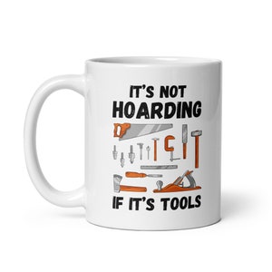 May include: White ceramic mug with a black and orange design. The mug features the text "It's not hoarding if it's tools" and an illustration of various tools, including a saw, hammer, screwdriver, and wrench.