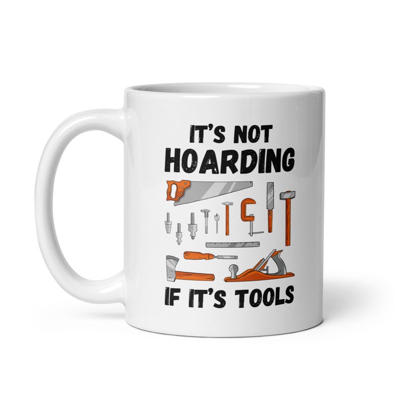 May include: White ceramic mug with a black and orange design. The mug features the text "It's not hoarding if it's tools" and an illustration of various tools, including a saw, hammer, screwdriver, and wrench.
