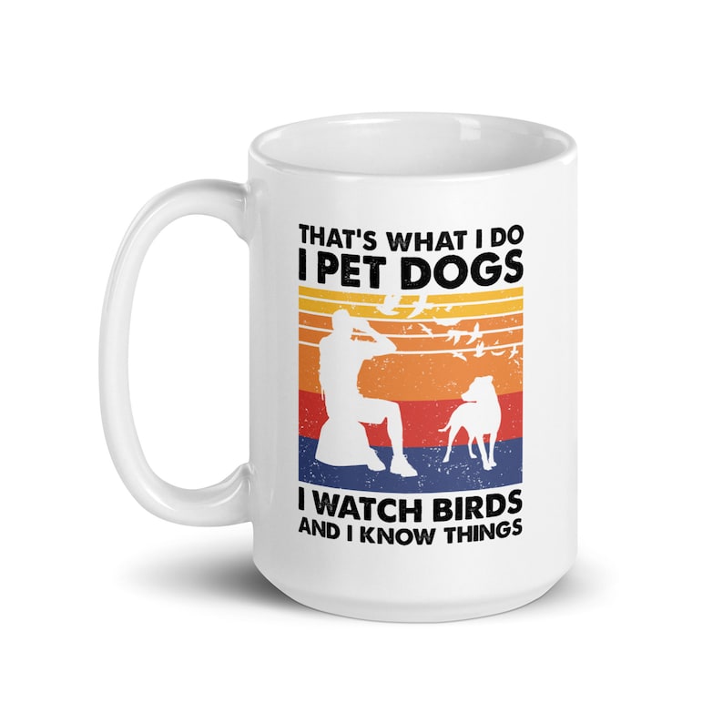 K&ouml;nnte beinhalten: Wei&szlig;e Keramiktasse mit einem Grafikdesign im Retro-Stil. Der Text lautet "That's what I do I pet dogs I watch birds and I know things". Die Grafik zeigt eine Person, die einen Hund streichelt und V&ouml;gel beobachtet.