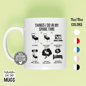 May include: White ceramic mug with a black design that says "Things I do in my spare time" and shows a series of illustrations of pinball machines. The text "100% Customizable Design" is in a black circle with a heart in the center. The mug is available in 11oz or 15oz sizes and in a variety of colors: white, red and white, blue and white, pink and white, and black and white.