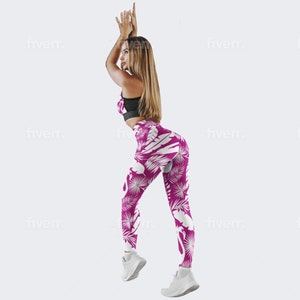 Könnte beinhalten: Eine Frau trägt einen schwarzen Sport-BH und pinkfarbene Leggings mit einem weißen Flamingo- und tropischen Blatt-Muster. Die Leggings sind figurbetont und zeigen ihre Figur.