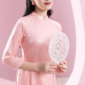 May include: A handmade wooden sign with the text "Welcome" in a playful font. The sign is painted white with a distressed finish, and features a decorative floral design in shades of pink and green. It measures approximately 12 inches wide.