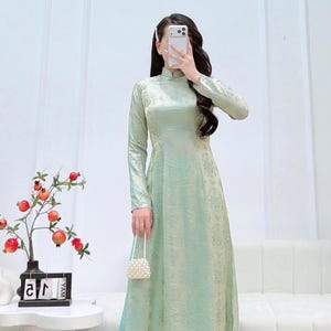 May include: A white ceramic mug with a black handle and the text "But First, Coffee" in a bold, black font. The mug is set against a blurred background, highlighting its clean design. The mug appears to be approximately 4 inches tall.