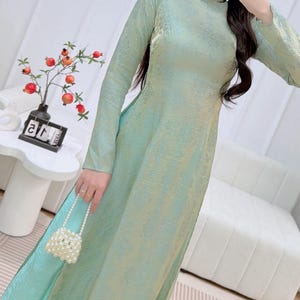 May include: A white ceramic mug with a black handle and the text "But First, Coffee" in a black, bold font. The mug is on a white surface.