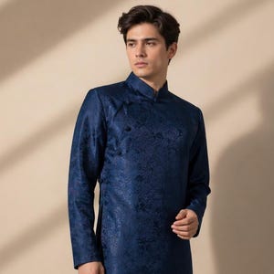 May include: A long-sleeved, navy blue tunic with a mandarin collar and floral pattern. The tunic has a button closure and a side slit. The garment is worn with black pants. The style is traditional and formal.