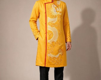 Op de afbeelding: Een lange, gele tuniek met een mandarijnkraag en rode bies, met een geborduurd drakenontwerp. De tuniek wordt gecombineerd met een zwarte broek en schoenen. De mouwen en de voorkant van de tuniek hebben ingewikkelde borduursels.