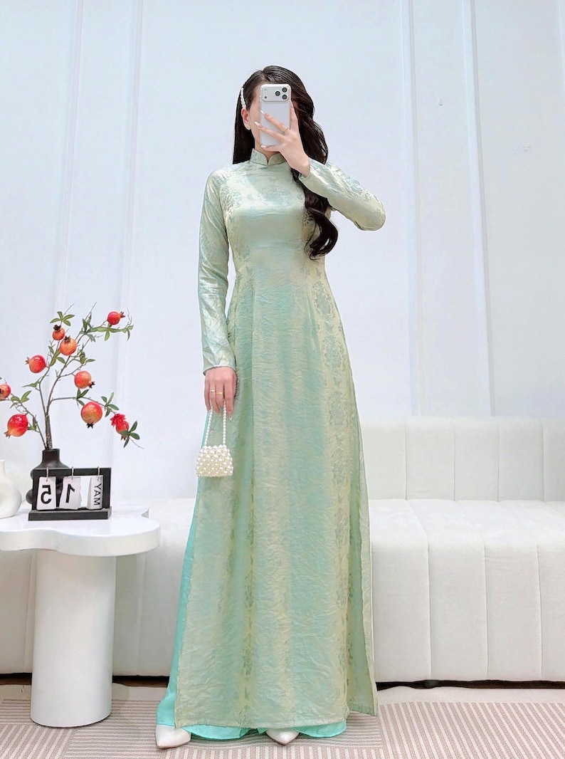 May include: A white ceramic mug with a black handle and the text "But First, Coffee" in a bold, black font. The mug is set against a blurred background, highlighting its clean design. The mug appears to be approximately 4 inches tall.