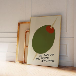 Könnte beinhalten: Eine grüne Olive mit roter Mitte ist mit einem Zahnstocher aufgespießt. Die Olive befindet sich auf einem weißen Hintergrund mit dem Text "NO MORE FOR ME! THANKS I'M STUFFED."