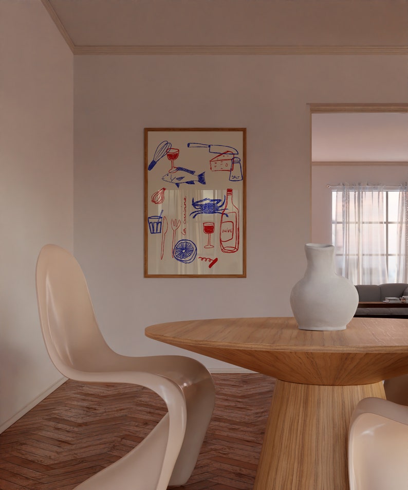 May include: A wooden dining table with a round top and a white ceramic vase with a white pitcher on top. Two white chairs are on either side of the table. A framed print with a red and blue illustration of food and drink is on the wall behind the table.