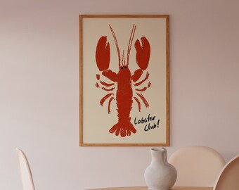 May include: A framed print of a red lobster with the text "Lobster Club!" on a cream background. The print is hanging on a light pink wall above a wooden table with two chairs.