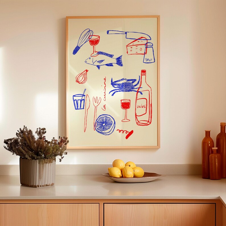 May include: A framed illustration of a kitchen scene with a red and blue color scheme. The illustration includes a fish, a crab, a bottle of wine, a glass of wine, a lemon, a whisk, a knife, a fork, a corkscrew, a bowl of onions, and a piece of cheese. The text "la cuisine" is written in blue on the illustration.