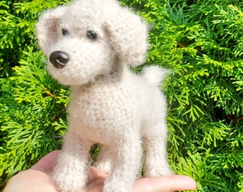 May include: A white crocheted dog toy with a fluffy texture. The toy is standing on a person's hand.
