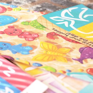 May include: A colorful game board with a variety of images, including a butterfly, a fish, a turtle, a snail, and a bear. The board is made of cardboard and has a light brown background. The text on the board reads "I've hold the little soul, the diafit's buddies".