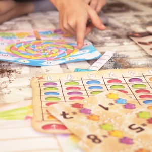 May include: A colorful game board with a spiral design and numbers 1 through 5. There are also several smaller game boards with jelly bean images and math equations.