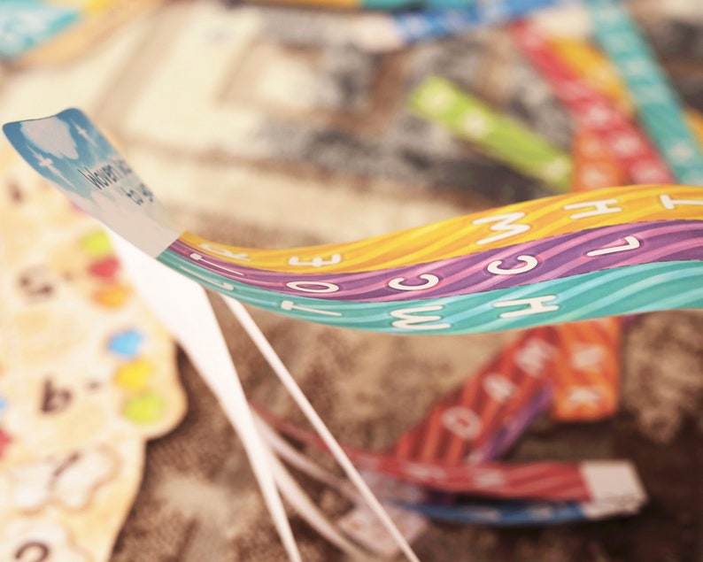 May include: A close-up of a colorful, multi-layered ribbon with the words "What We Do" printed on the top layer. The ribbon is made of three different colors: orange, purple, and blue. Each color has a wavy pattern and white letters.