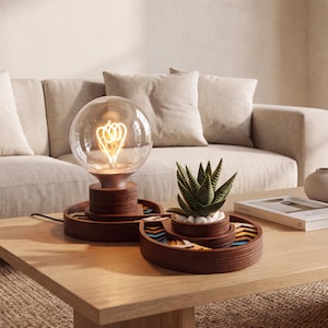 Puede incluir: Una lámpara de mesa de madera con una bombilla esférica grande y transparente que muestra un filamento brillante, junto a una bandeja circular de madera a juego que contiene una pequeña planta suculenta verde y detalles geométricos coloridos.