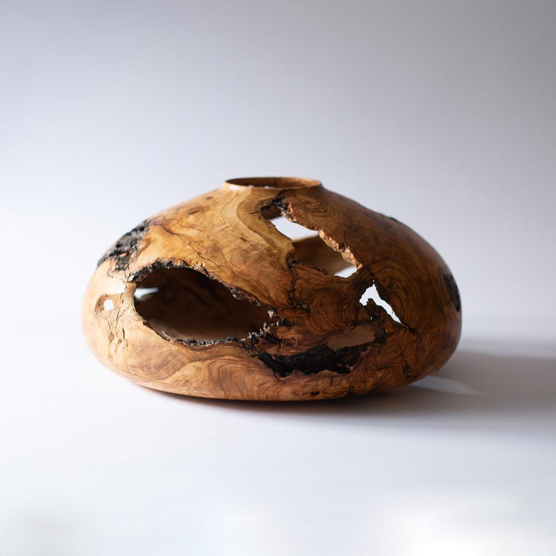 Olive wood vase centerpiece showing dramatic grain and wabi-sabi natural holes.