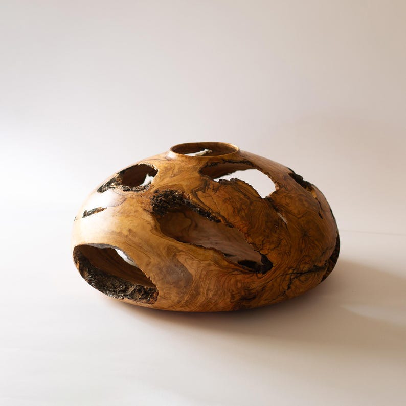 Entryway decor wood vase, sculptural hollow form in olive wood, minimal backdrop.