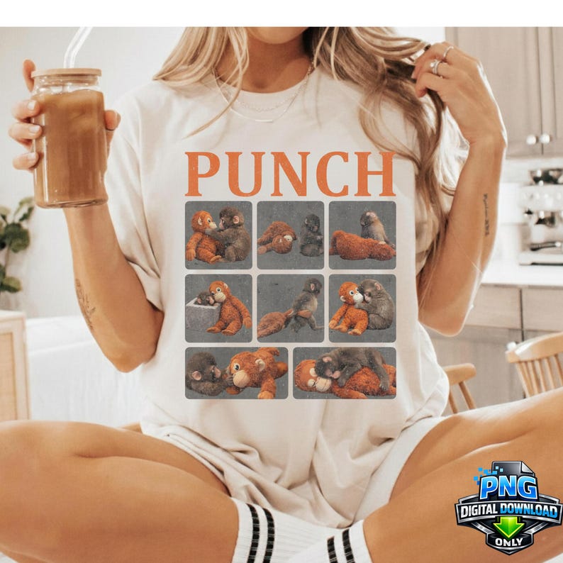 May include: Cream-colored t-shirt with the word "PUNCH" in orange block letters. The shirt features a grid of nine images of monkeys. The person is holding a glass of iced coffee.