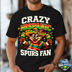 May include: Black t-shirt with a colorful graphic featuring a cartoon bear wearing a sombrero and holding maracas. The text on the shirt reads "CRAZY HISPANIC SPURS FAN" in white, red, and green.