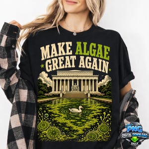 Könnte beinhalten: Ein schwarzes T-Shirt mit einem Grafikdruck, der den Text "MAKE ALGAE GREAT AGAIN" in Beige und Grün zeigt. Das Design stellt das Lincoln Memorial über einem grünen, algenbedeckten Reflexionsbecken mit einer weißen Ente in der Mitte dar.