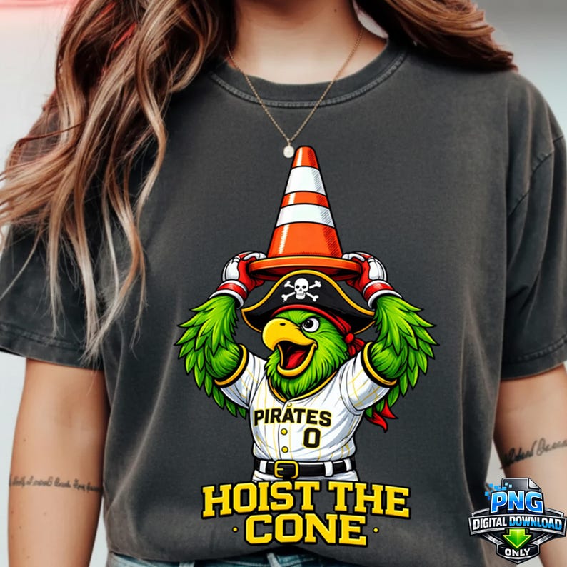 May include: Dark gray t-shirt featuring a cartoon parrot wearing a pirate hat and baseball jersey with the text "Pirates" and "0". The parrot is holding an orange and white traffic cone. The text "HOIST THE CONE" is below the parrot.