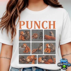 May include: White t-shirt featuring the word "PUNCH" in orange block letters above a grid of nine squares. Each square contains a different image of a plush monkey. The monkeys are in various poses, some hugging and some wrestling.