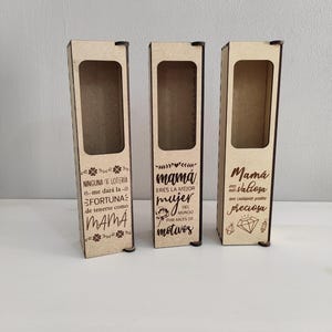 May include: Three wooden gift boxes with rectangular cutouts. Each box has a different Spanish phrase etched on it, including "Mamá eres la mejor mujer del mundo por miles de motivos."