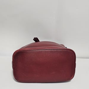 以下が含まれることがあります： 引き紐で閉じる、ワインレッドの革製のバケツバッグです。