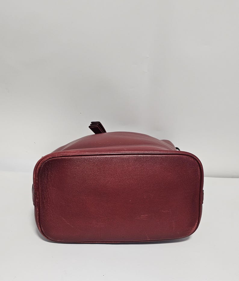 以下が含まれることがあります： 引き紐で閉じる、ワインレッドの革製のバケツバッグです。