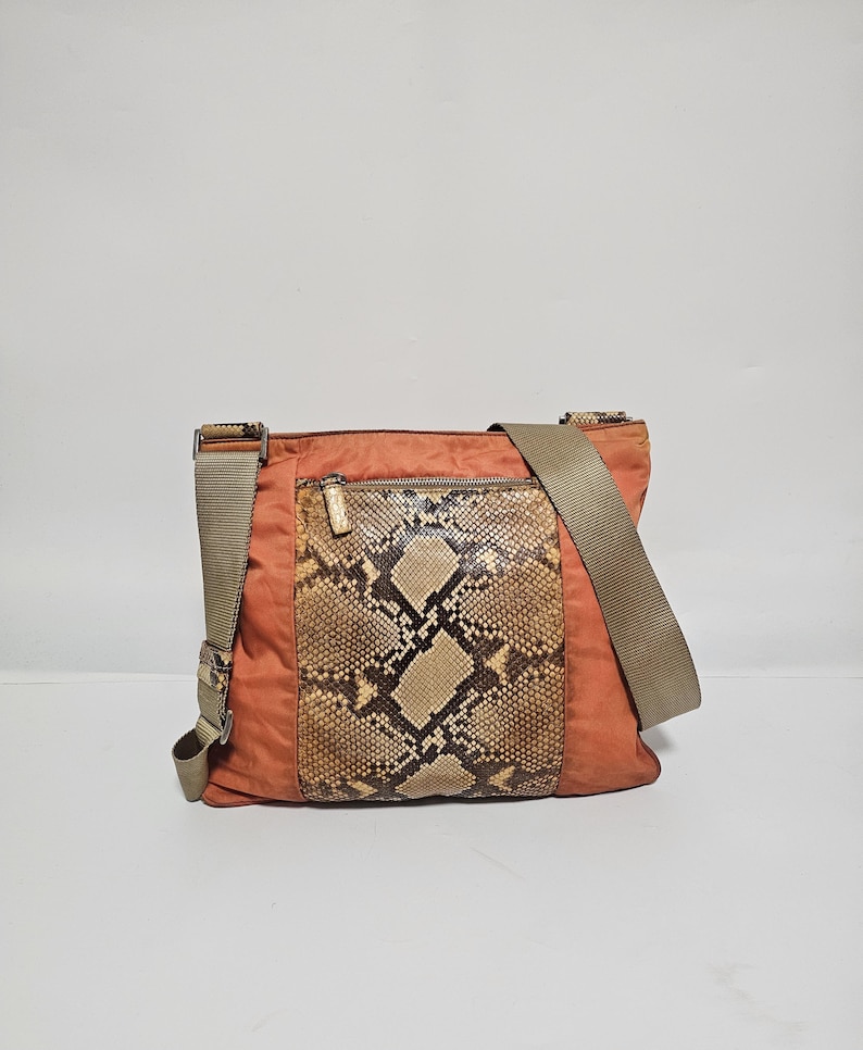 Peut inclure: Sac bandouli&egrave;re orange avec un panneau en peau de serpent sur le devant. Le sac est dot&eacute; d'une longue bandouli&egrave;re r&eacute;glable et d'une poche zipp&eacute;e. Le sac est fait d'un mat&eacute;riau durable.