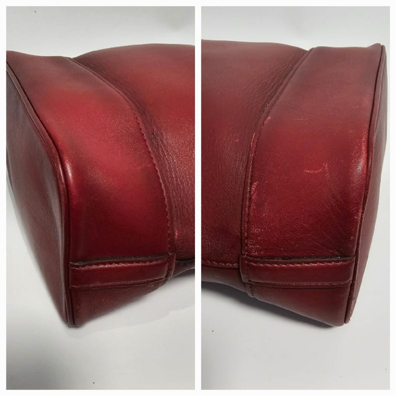 以下が含まれることがあります： 赤い革製のハンドバッグの底部のクローズアップ。バッグは底の縁にステッチされた縫い目があります。