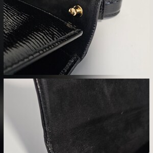 K&ouml;nnte beinhalten: Nahaufnahme einer schwarzen Ledergeldb&ouml;rse mit gl&auml;nzendem Finish. Die Geldb&ouml;rse hat einen goldfarbenen Verschluss und eine strukturierte Oberfl&auml;che. Die Innenseite scheint aus Wildleder zu sein. Ein klassisches Accessoire.