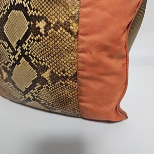 Peut inclure: Gros plan sur un sac &agrave; main avec un motif peau de serpent et un panneau en tissu orange br&ucirc;l&eacute;. La section en peau de serpent pr&eacute;sente un motif marron et beige. Le sac a une fermeture &eacute;clair.