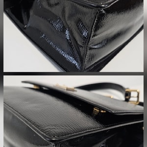 K&ouml;nnte beinhalten: Nahaufnahme einer gl&auml;nzenden schwarzen Handtasche mit Klappenverschluss und goldfarbener Hardware. Die Tasche hat eine strukturierte Form und einen Schulterriemen. Das Lacklederfinish reflektiert das Licht und hebt die Textur und das Design der Tasche hervor.