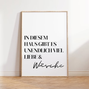 Könnte beinhalten: Ein gerahmter Druck mit weißem Hintergrund und schwarzem Text, der "In diesem Haus gibt es unendlich viel Liebe & Wäsche" lautet.