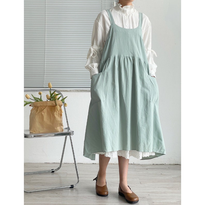 Peut inclure: Une robe chasuble vert clair avec une bordure en dentelle blanche et deux poches. La robe a un col rond et des bretelles r&eacute;glables.