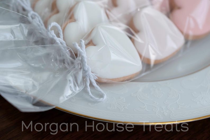 Close up side shot of white baker's twine tie closure with sleeve of cookies fading to right. Cookies rest on white china plate with gold rim. Morgan House Treats watermark at bottom of image.