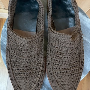 K&ouml;nnte beinhalten: Ein Paar braune geh&auml;kelte Slipper mit einem gewebten Muster.