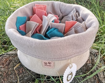 May include: A beige felt dog toy basket with a brown "Handmade" label and a white tag featuring a lion illustration. The basket is filled with colourful felt pieces in shades of pink, teal, and grey.