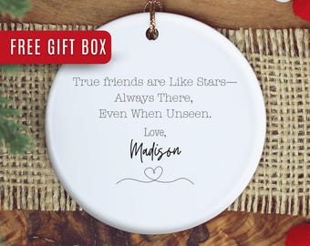 May include: White ceramic ornament with a gold string for hanging. The ornament has the text "True friends are Like Stars—Always There, Even When Unseen. Love, Madison" in black script. A red banner reads "FREE GIFT BOX".