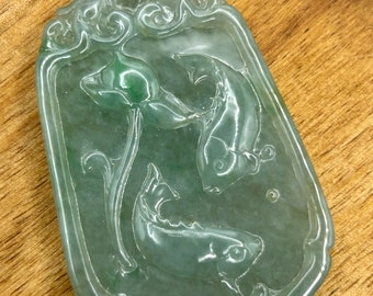May include: A jade pendant with a gold bail, featuring a carved design of two fish swimming around a lotus flower.