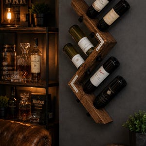 May include: A wooden wine rack on a dark grey wall, displaying several wine bottles. The rack has a zig-zag design and is made of dark wood. The bottles are various colours, with visible labels. The background includes a bar sign and a shelf with liquor bottles.