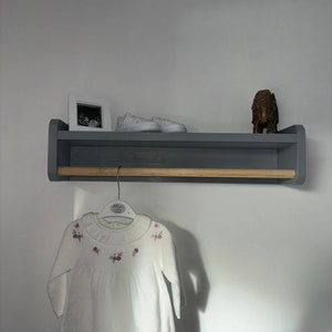 Nursery shelf with clothes hanger