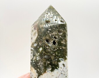 Puede incluir: Una punta de cristal de ágata verde, blanca y marrón con un patrón único moteado. El cristal está pulido y tiene un acabado liso y brillante.