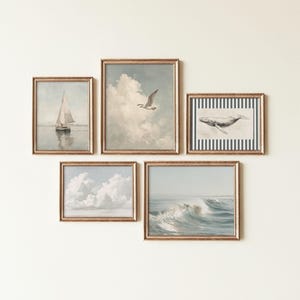 Könnte beinhalten: Ein Satz von fünf gerahmten Kunstdrucken mit goldfarbenen Rahmen. Die Drucke zeigen nautische Themen, darunter ein Segelboot, eine Möwe in den Wolken, ein Wal und Meereswellen. Die Kunstwerke haben einen Vintage-Aquarellstil.