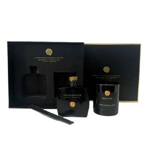 May include: A black gift box set with gold accents containing a black reed diffuser bottle, a black candle with a gold lid, and a black stick. The candle has a gold label that reads "Rose Oud" and "Luxury Scented Candle". The diffuser bottle has a gold label that reads "Luxury Diffuser" and "Private Collection". The box has a gold label that reads "Luxury Home Fragrance Gift Set" and "Reed Diffuser | Scented Candle".