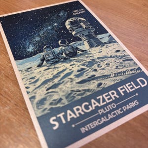 May include: A vintage-style poster with a blue and white color scheme. The poster features two astronauts sitting on a moon-like surface, looking up at a starry sky. The text on the poster reads "Stargazer Field - Pluto - Intergalactic Parks" and "See the Galaxy".