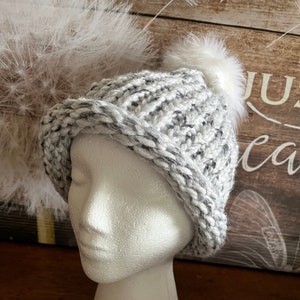 White with black mixed in knitted hat with White removable pom pom. Thick and warm. Perfect for the cold winter.